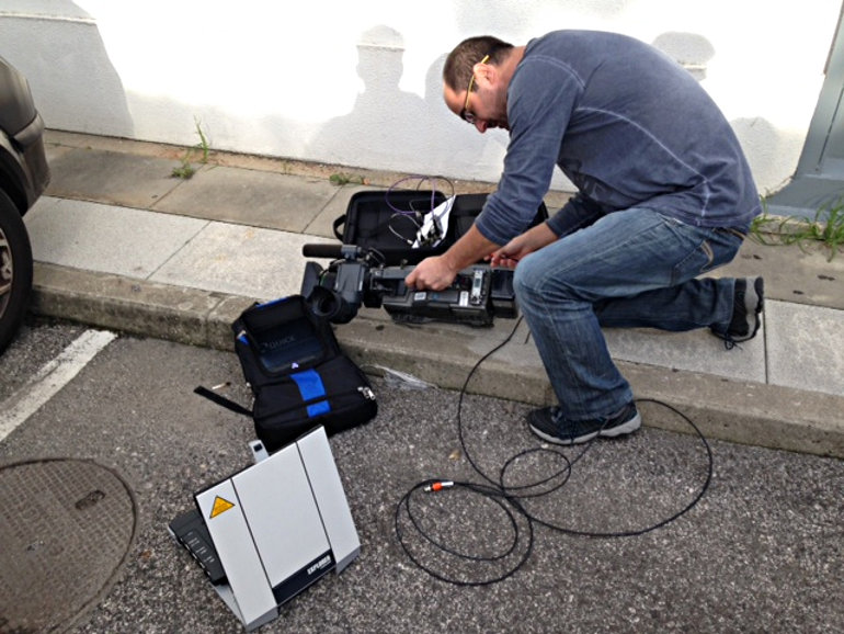 A TV2 Denmark broadcast journalist using Quicklink to upload standard HEVC video via a portable Inmarsat BGAN HDR terminal